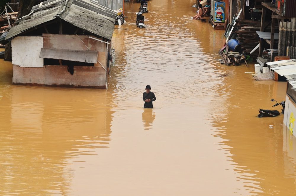 Flooding engulfs homes and a person stands in the water.